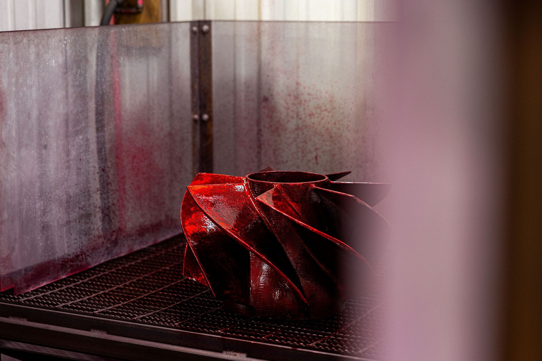 A finish-machined centrifugal pump impeller during liquid-penetrant inspection — red dye penetrant highlights any surface-breaking indications on vane surfaces before the part ships.
