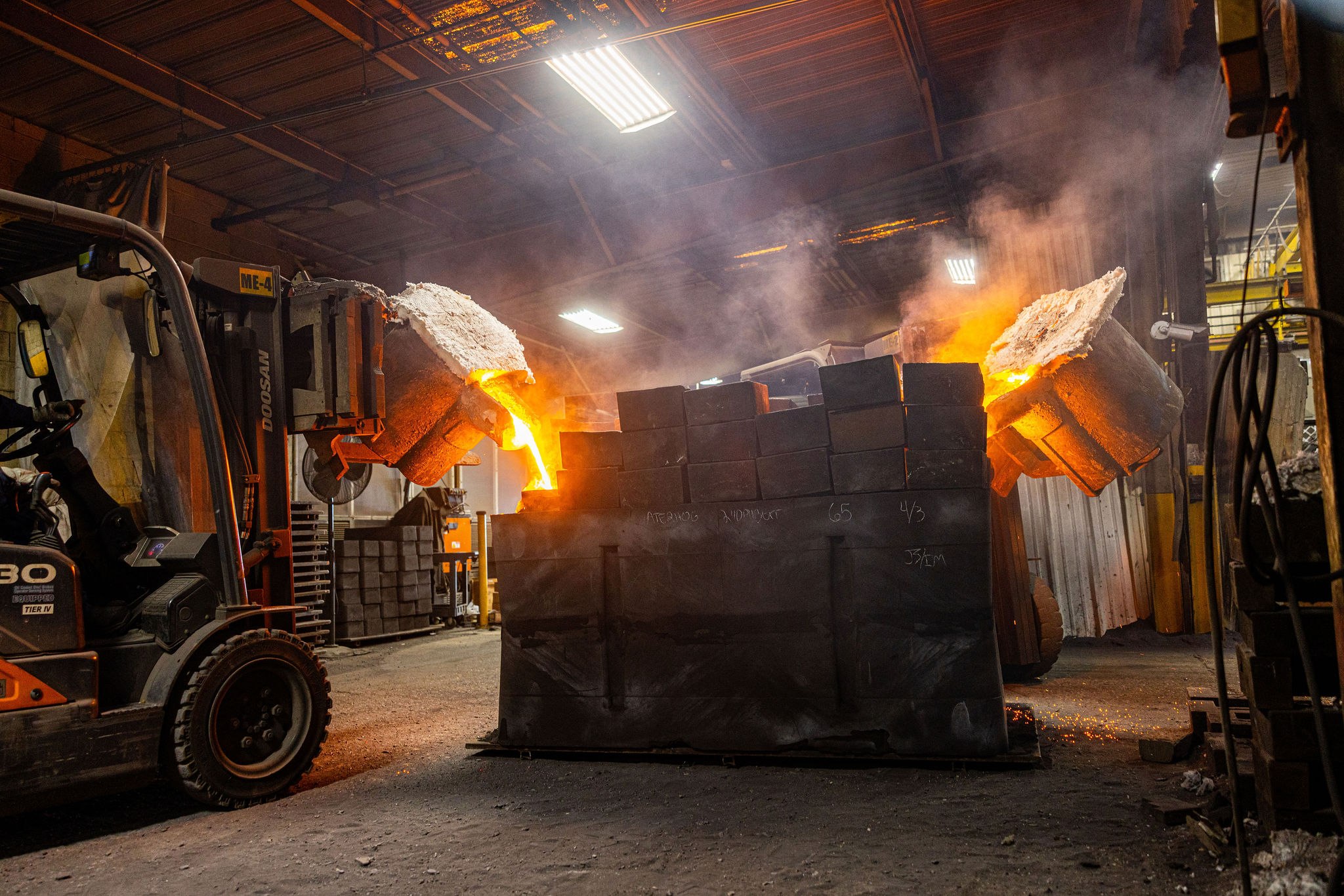 Molten stainless steel being poured into a 3D-printed sand mold on the pour floor — the patternless workflow that makes 1–100 piece CD4MCuN duplex runs economical.